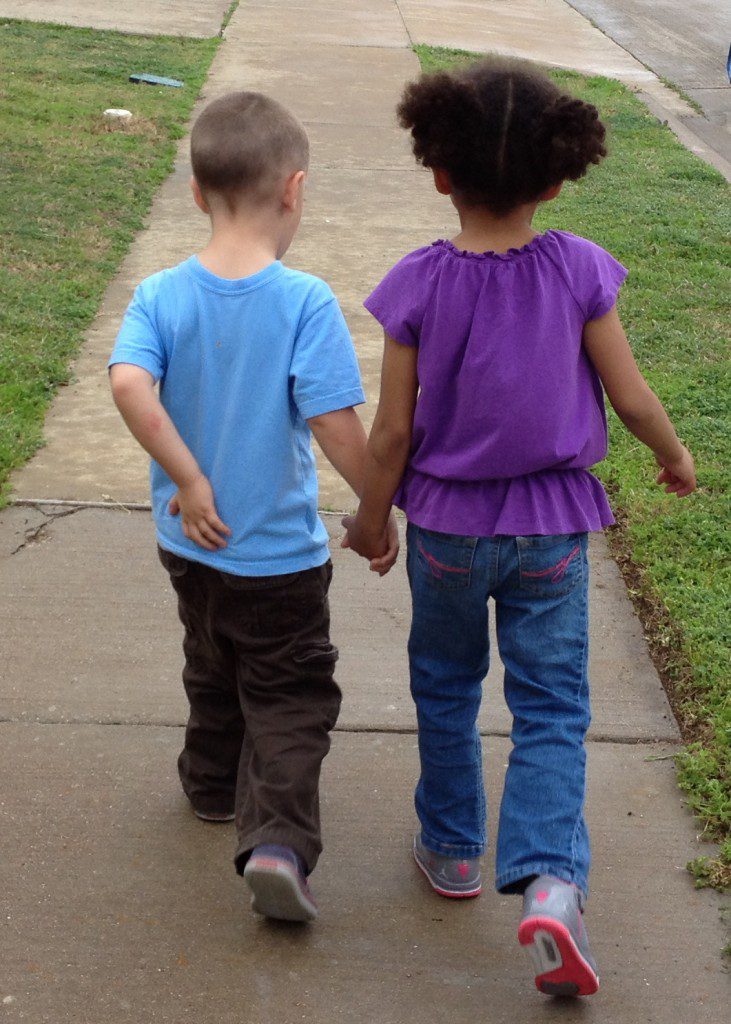 2 kids holding hands. we all need friends